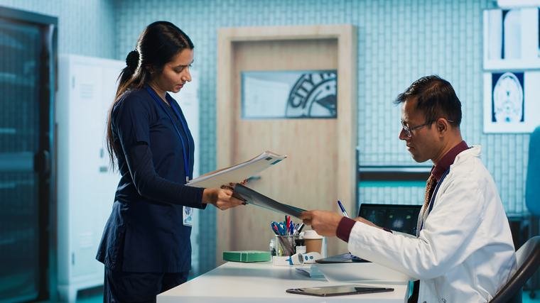 Nurse handing an X-ray film to the reviewing physician